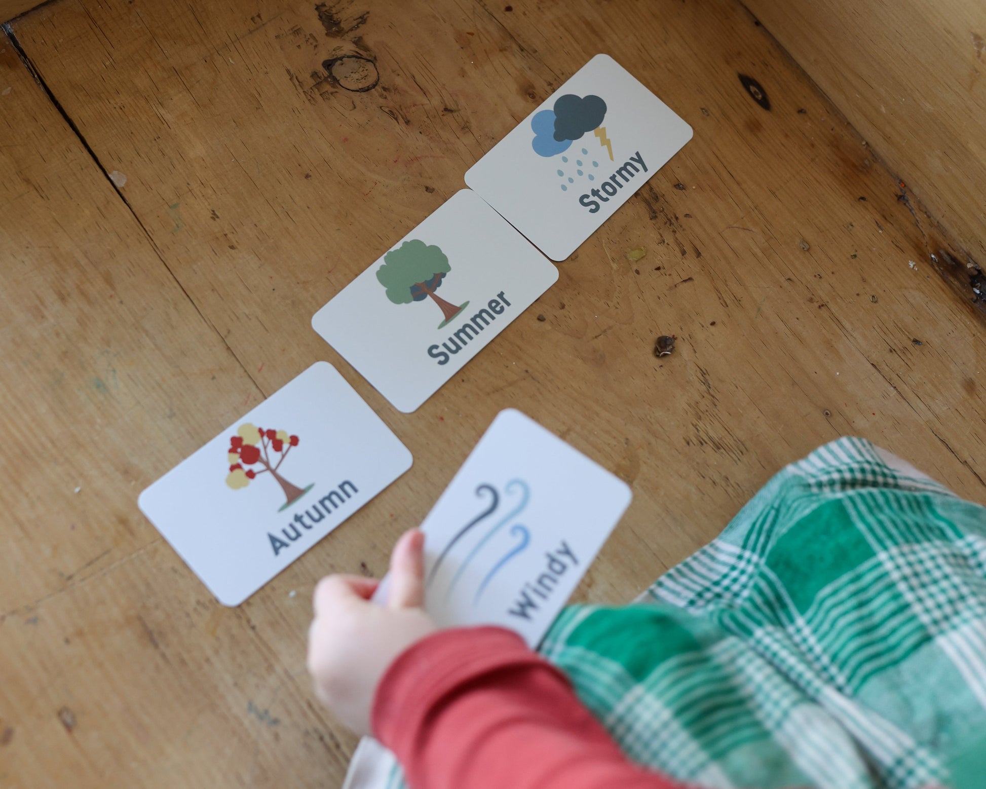 Child interacting with educational cards on a wooden surface